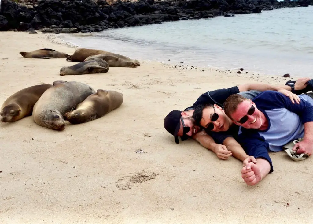 Gay cruise group posing with sea lions on a Galapagos beach