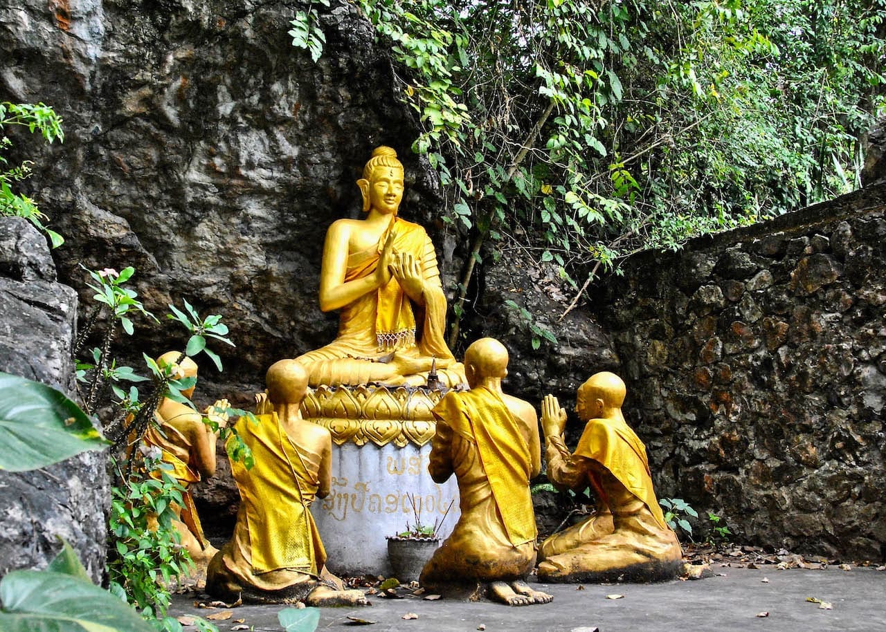 Four monk statues praying to a Buddhist Statue in Cambodia.