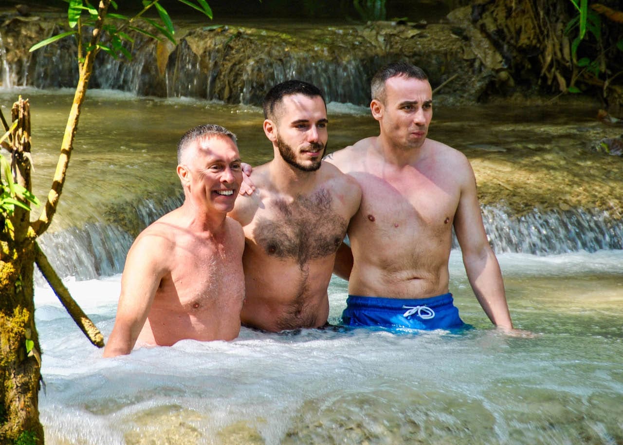Kevin Robitaille and two other men take a dip in Kuang Si Falls on a gay tour with Out Adventures.
