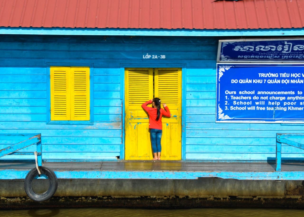 A Cambodian girl peeks into a brightly coloured school on the bank of the Mekong River.