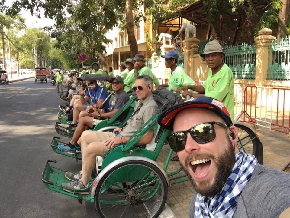 Robert Sharp taking a selfie with a group of gay travellers lined up on rickshaws in Siem Reap.