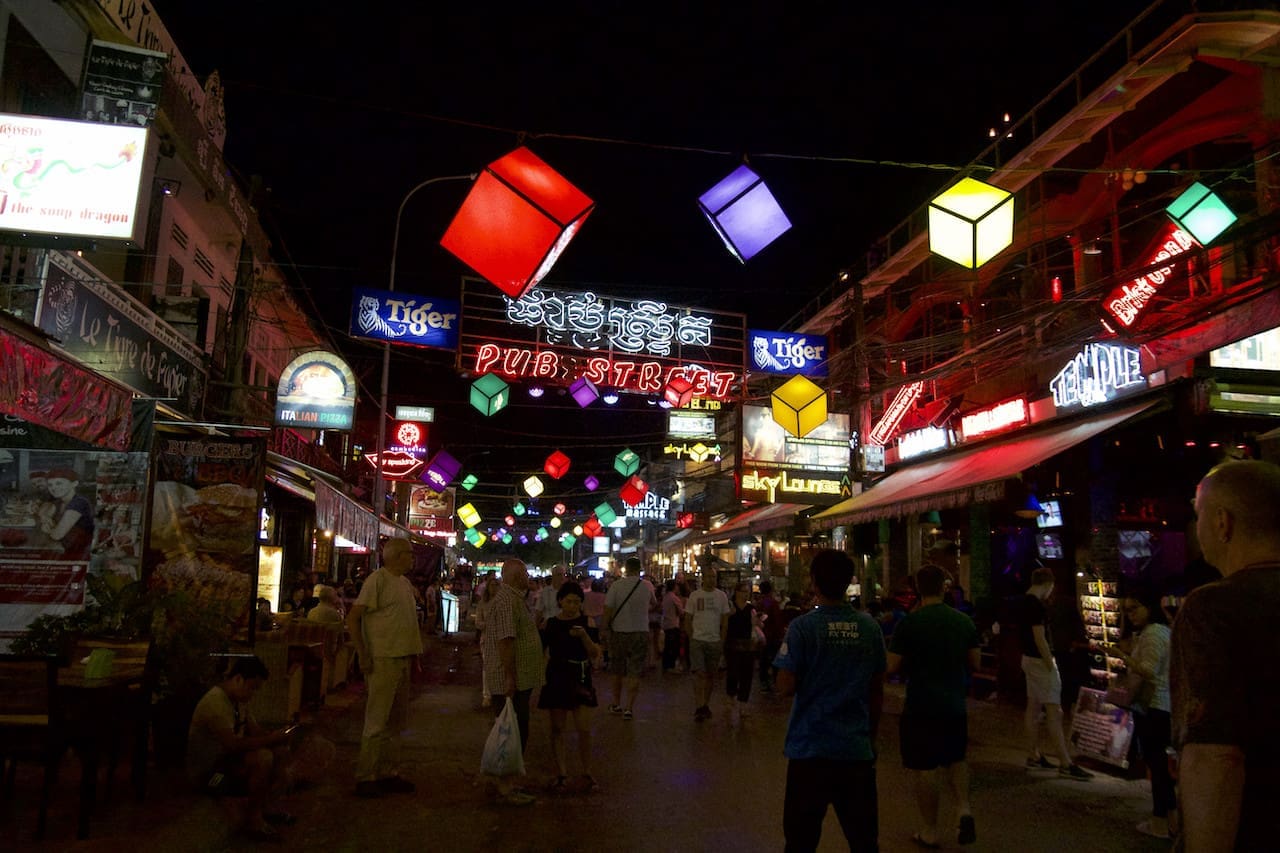 A neon sign saying 'Pub Street' glows brightly above a pedestrian packed street in Siem Reap.
