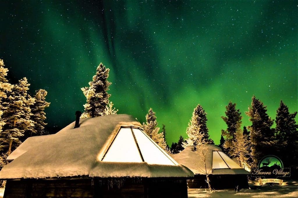 The Northern Lights dancing above the glass-roofed cabins featured on Out Adventures' gay Finland tour.