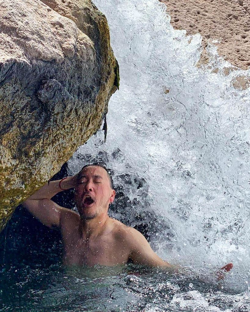 A gay traveller "showering" under a small waterfall in a Chilean hot spring.