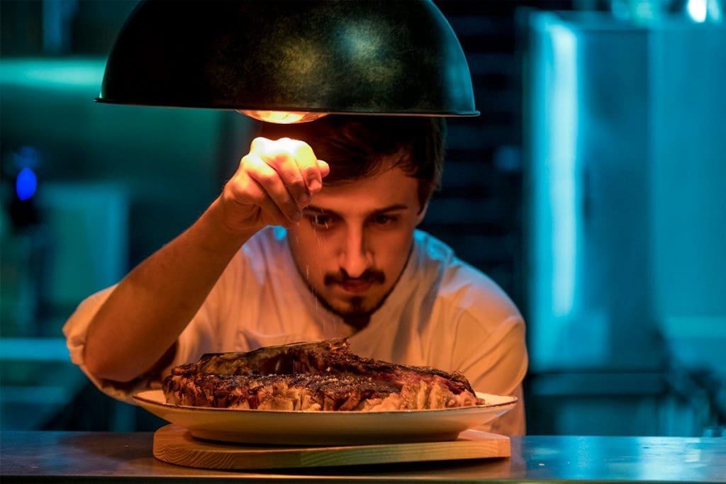A chef at Muu Steakhouse puts the finishing touches on a grilled steak.