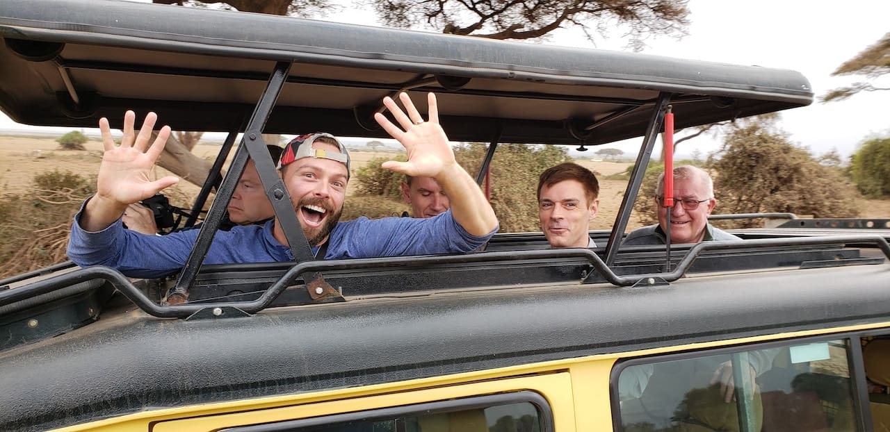 A group of jet setters having a good time inside a safari vehicle.
