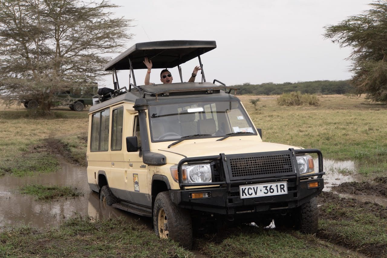 A traveller laughs as his safari vehicle gets stuck in a mud pit.
