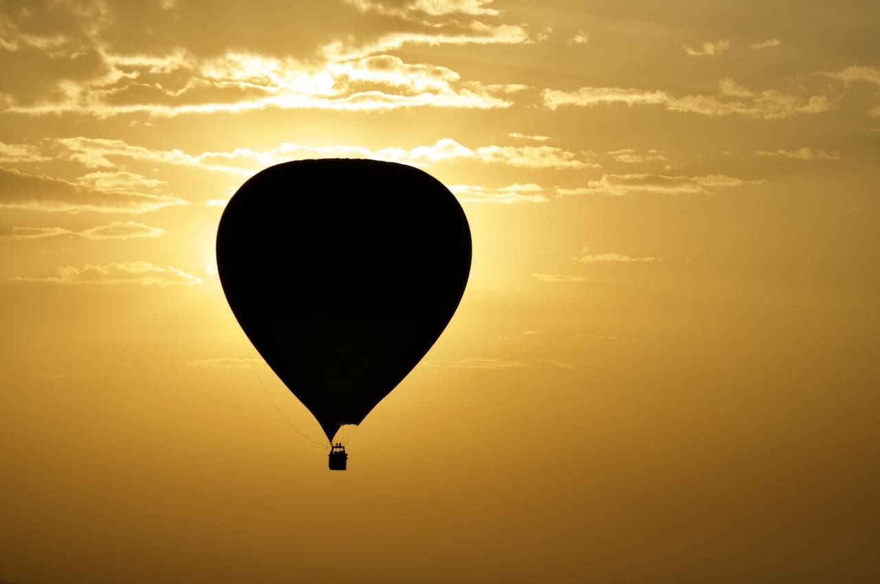 A lone hot air ballon is backlit by the morning sun in Kenya.