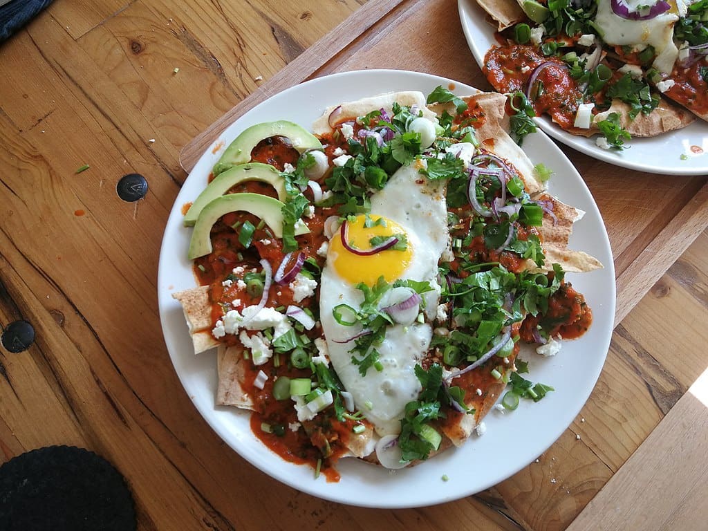 A platter of chilaquiles served with avocado and fried egg.