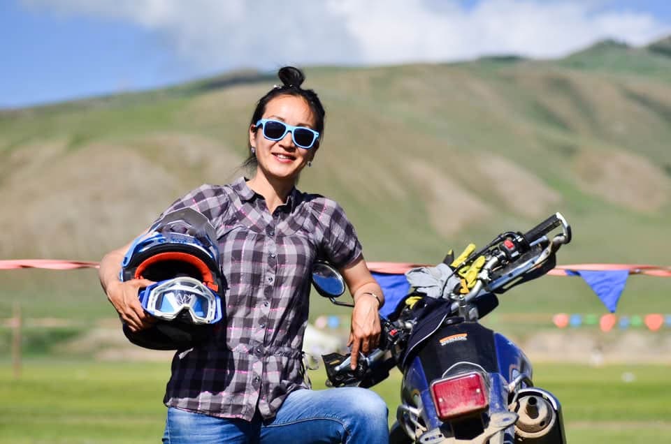 Out Adventures' local Mongolia guide posing with a motorcycle in the countryside.