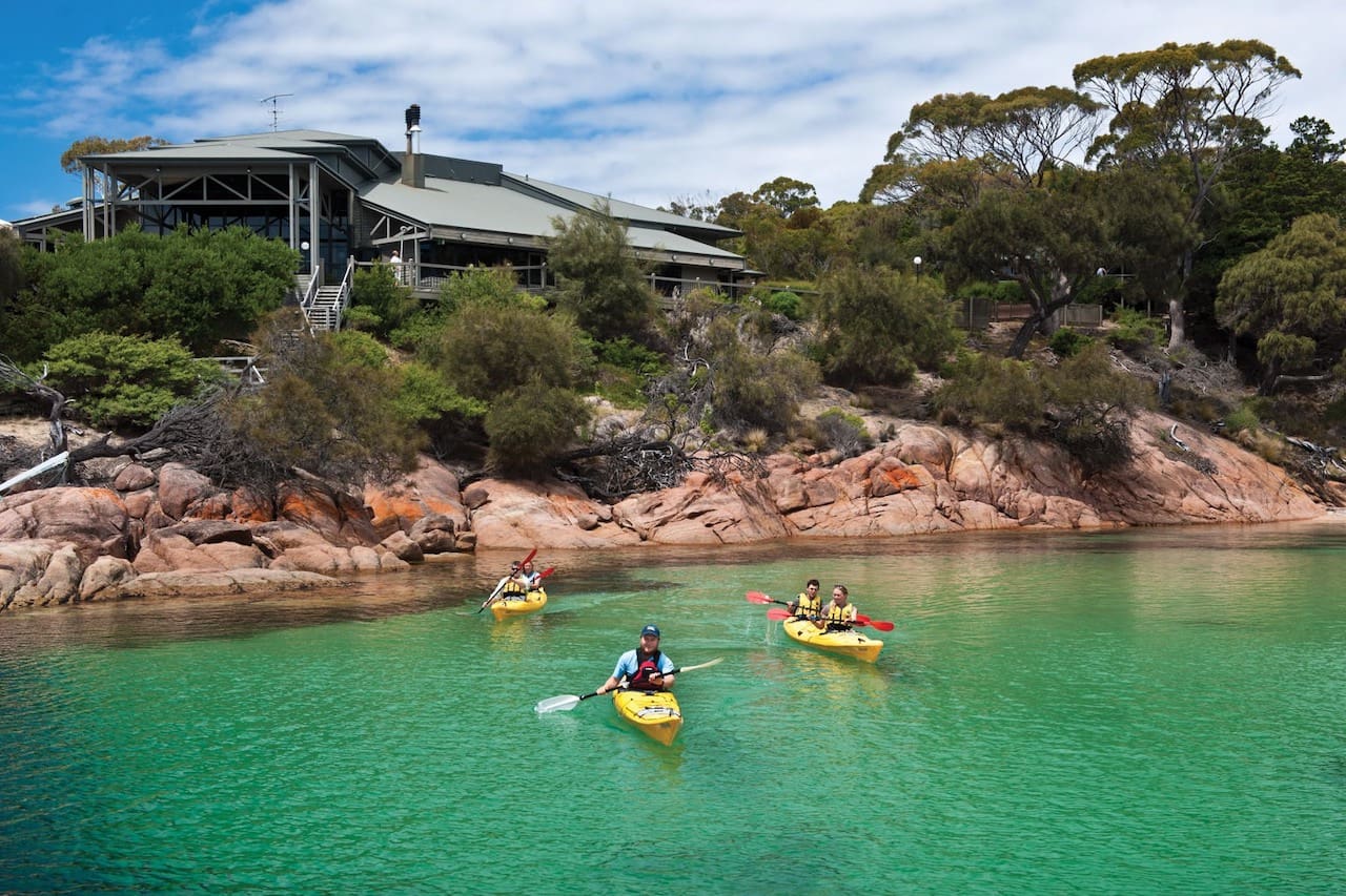 Three kayakers paddle out from Freycinet Lodge on Richardson's Beach.
